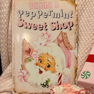 Pink Santa's Peppermint Sweet Shop Metal Sign on bed